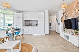 a kitchen with white cabinets and a table and chairs at Bavaro 50 by Alezzi Resort in Mamaia Sat/Năvodari
