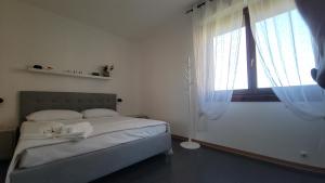 a white bedroom with a bed and a window at Il Tramonto in Elmas