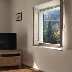 a living room with a flat screen tv and a window at Charme a Corniglio - Suite Cervo in Corniglio
