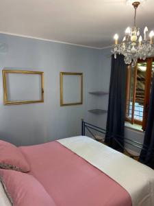 a bedroom with a pink bed and a chandelier at Cascina Vica Biella in Andorno Micca