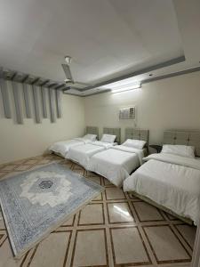 a room with four beds and a rug on the floor at شقة واسعة بحي الدوحة لـ 10 أشخاص 6دقائق للبحر in Yanbu