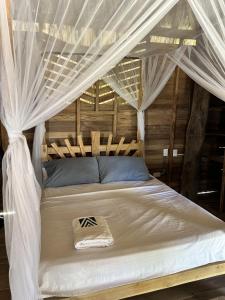 a bed with a canopy with white drapes at Bungalow Palmar del Viento by AMAUNA in Moñitos
