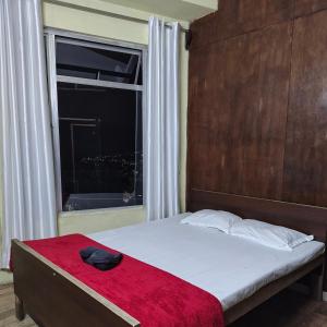 a bed with a red blanket and a window at Mizotel in Āīzawl
