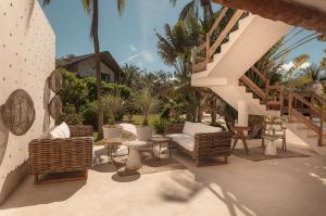 a patio with wicker chairs and tables and stairs at Ser Casasandra Boutique Hotel in Holbox Island