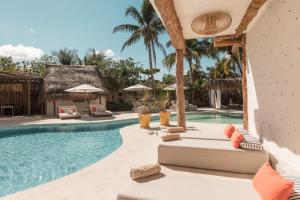 a pool at a resort with lounge chairs and umbrellas at Ser Casasandra Boutique Hotel in Holbox Island
