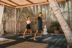 a man and a woman doing yoga in a pavilion at Ser Casasandra Boutique Hotel in Holbox Island