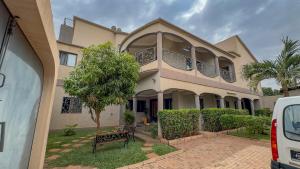 a house with a tree in front of it at Kipress Lodge Hôtel in Ouagadougou