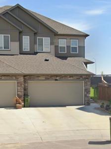 a house with two garage doors in a driveway at Modern Comfort Stay Near Airport in Edmonton