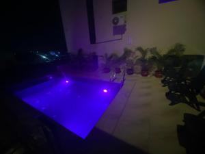 a dark room with a pool with purple lights at Teestone Hotels and Apartment Ikeja in Lagos