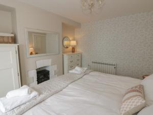 a bedroom with a white bed and a fireplace at Arosfa in New Quay