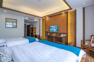 a hotel room with two beds and a tv at Zhangjiajie Yun Hai Hotel- Ancient Chinese Style Hotel,Tea Culture Experience, Realxing Class,Free Breakfast ,Local Travel Guide and Book Tickets, Gem Perporty in Zhangjiajie