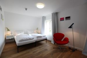 1 dormitorio con 1 cama y 1 silla roja en einzigartig - Das kleine Hotel im Wasserviertel en Lüneburg