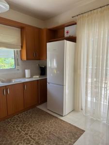 a kitchen with a white refrigerator and a window at Seaside House 2 in Polychrono +24 photos