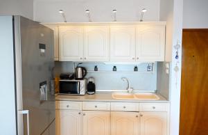 a kitchen with white cabinets and a sink and a microwave at Thalia Sea View Apartment in Nea Peramos
