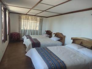 a group of three beds in a room at TAQUILE LODGE Perú in Huillanopampa