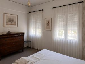 a bedroom with white curtains and a bed and a dresser at Aggelina's Apartment in Zakynthos