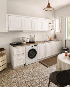 a kitchen with white cabinets and a washing machine at Aggelina's Apartment in Zakynthos