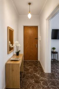 a hallway with a wooden door and a table with flowers on it at Aggelina's Apartment in Zakynthos