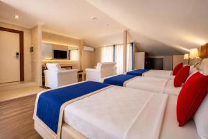 a bedroom with two beds with red and blue pillows at Kleopatra Micador Otel in Alanya