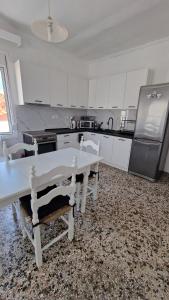 a kitchen with white cabinets and a white table and chairs at Xilagani Central House in Xilaganí