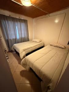 two beds in a small room with a window at Servicios Alvarez in Rincon de los Sauces