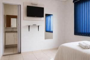 a bedroom with a bed and a television on the wall at Pousada Lagus Pan in Capitólio +2 photos