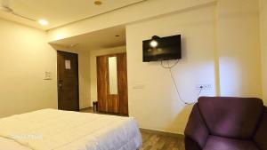 a bedroom with a bed and a tv on the wall at Hotel ShivInn in Gandhinagar +10 photos