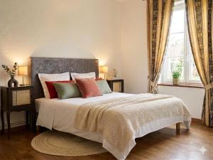 a bedroom with a large bed with red and green pillows at Le CLOS D'ETRETAT in Les Loges