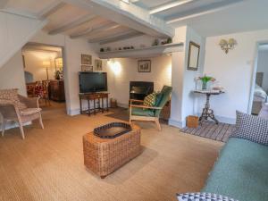 a living room with a couch and a tv at Wolvesacre Mill Cottage in Whitchurch