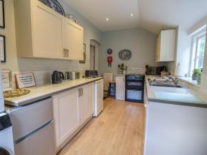 a large kitchen with white cabinets and wooden floors at Wolvesacre Mill Cottage in Whitchurch
