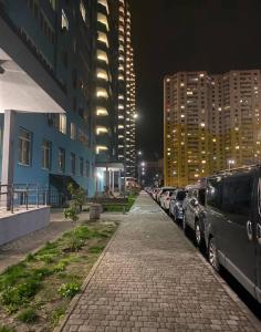 a city street with cars parked next to tall buildings at Уютная комната в квартире в ЖК Одесский Бульвар in Teremki