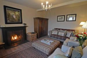 a living room with a couch and a fireplace at Kates Cottages Kinnighallen in Spott