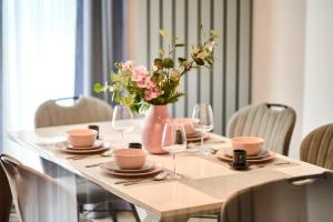 ein Tisch mit Gläsern und einer Vase mit Blumen darauf in der Unterkunft Bavaro 28 by Alezzi Resort in Mamaia Nord – Năvodari