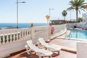 a balcony with two chairs and a swimming pool at Sweet Home in Puerto Rico de Gran Canaria