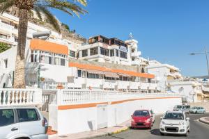 a street with cars parked in front of a white building at Sweet Home in Puerto Rico de Gran Canaria