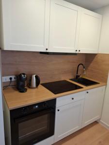 a kitchen with white cabinets and a sink and a stove at Levanda apartment in Visaginas
