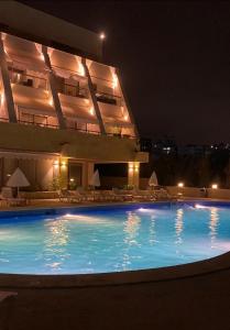a large swimming pool in front of a building at night at chalet in saint remon in Al ‘Ayn +9 photos