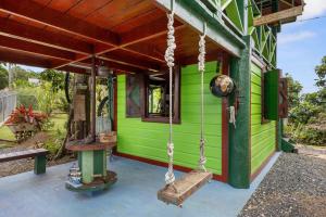 a green house with a porch with a swing at The Ceiba Villa by Otium in Aguas Claras