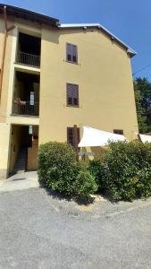 ein gelbes Gebäude mit Balkon und Büschen davor in der Unterkunft Camillo Benso in Bernareggio