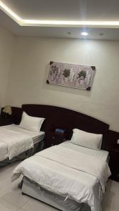 a room with two beds and a picture on the wall at شقق فندقية 2 in Buraydah +4 photos