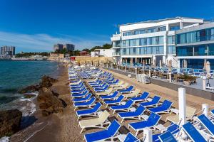 a row of lounge chairs on a beach next to a building at Boutique Hotel Portofino in Odesa