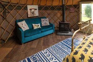 a living room with a blue couch and a stove at Sunbank Yurt in Llangollen