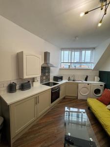a kitchen with white cabinets and a couch in a room at The Recharge Loft in Durham