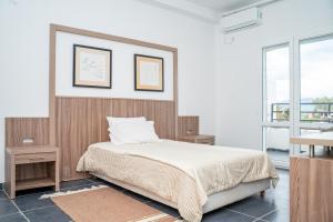a bedroom with a bed and two tables and a window at Rassyl Résidence in Jendouba