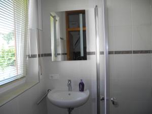 a white bathroom with a sink and a mirror at Ferienwohnung Wünsche in Weißensberg
