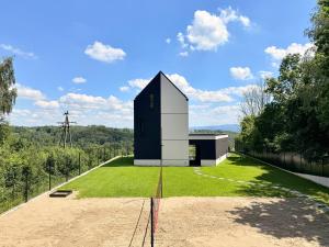 a small black and white building on a grass field at The East House ONE in Łapanów