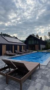a large swimming pool with lounge chairs next to a building at Goldhill villa in Yaremche