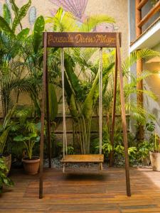 a swing with a sign in front of plants at Pousada Divino Milagre in Passo de Camarajibe