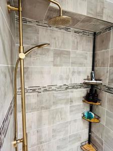 a shower in a bathroom with a tile wall at Le Faubourg St Martin Gold&Green in Senlis