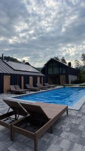 a large swimming pool with lounge chairs next to a building at GoldHill villas 9 in Yaremche